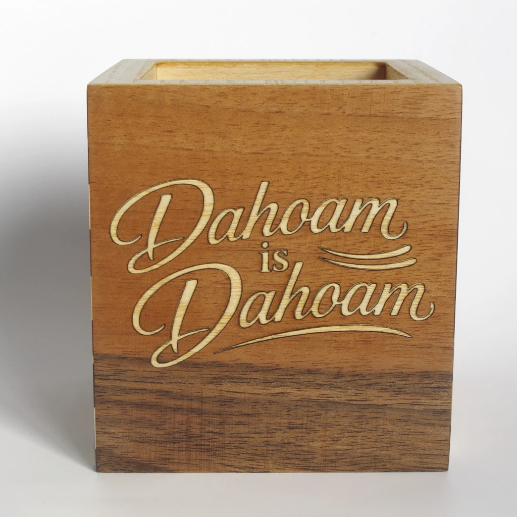 Seitenflaeche des Stiftehalters mit dem Schriftzug Dahoam is Dahoam in hellem Holz auf rotbrauner Flaeche